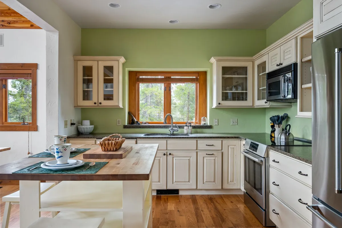 A spacious, inviting kitchen with a large island, stainless steel appliances, and a window offering a picturesque view. The scene features ample cabinetry, perfect for storing premium cookware, and the layout encourages both cooking and entertaining. The warm atmosphere and visible baking activity suggest family-friendly functionality and space for group gatherings.
