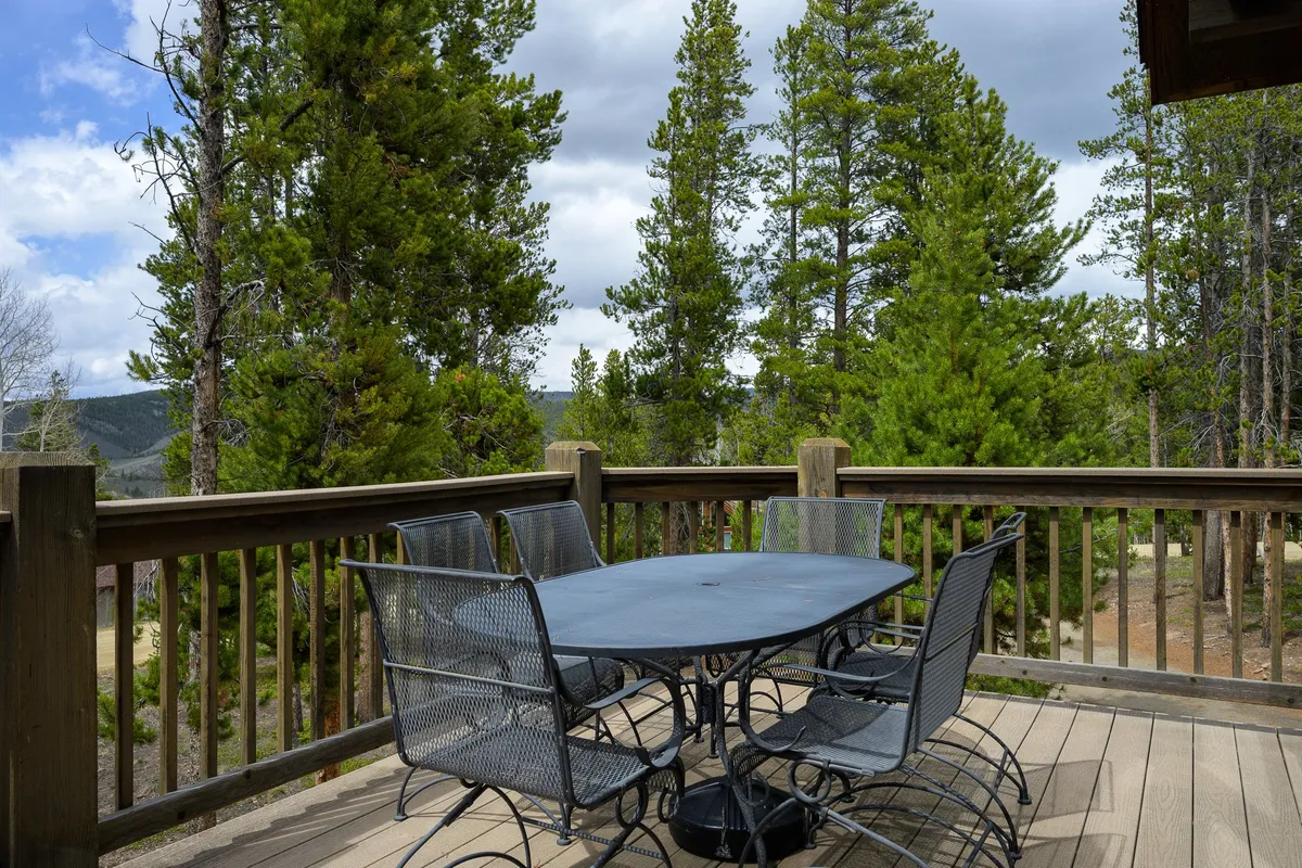 An inviting outdoor dining table is set amidst lush trees with a stunning mountain view in the background. The scene evokes serenity and a sense of escape—perfect for guests seeking both relaxation and memorable experiences in a beautiful natural setting.