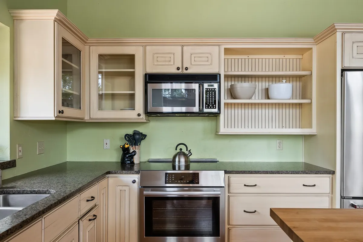 A modern kitchen layout featuring stainless steel appliances, a spacious granite countertop for meal prep, and open shelving for easy access to premium cookware. The welcoming atmosphere invites multiple people to cook together, making it ideal for group meal preparation and entertaining.