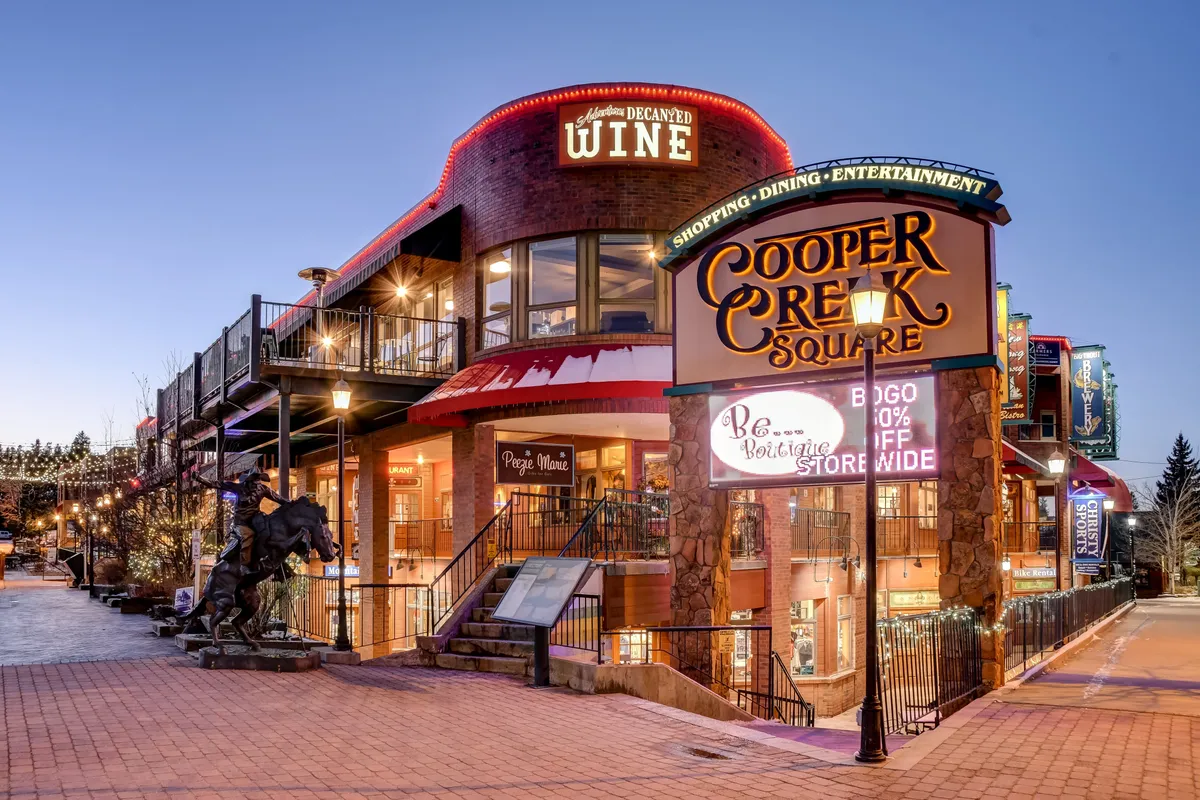 This image captures the festive, vibrant atmosphere of a local shopping and dining hub, Cooper Creek Square, featuring signage, a wine shop, and decorative elements. It represents a nearby destination for dining and entertainment, easily accessible from the lodge.